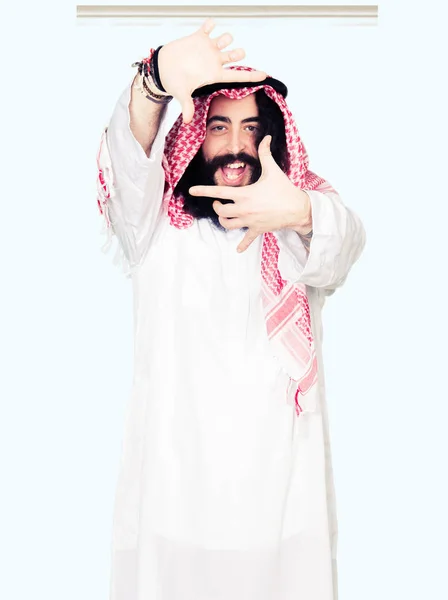アラビア ビジネスの男性は 長い髪を手で作るフレームと幸せそうな顔で指を笑顔の伝統的なクーフィーヤ スカーフ着用と 創造性と写真のコンセプト — ストック写真