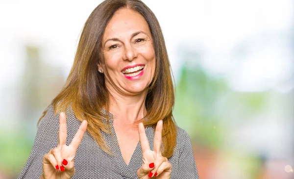 美しい中年女性実業家の勝利のサインをやって指を表示するカメラを笑みを浮かべてします — ストック写真