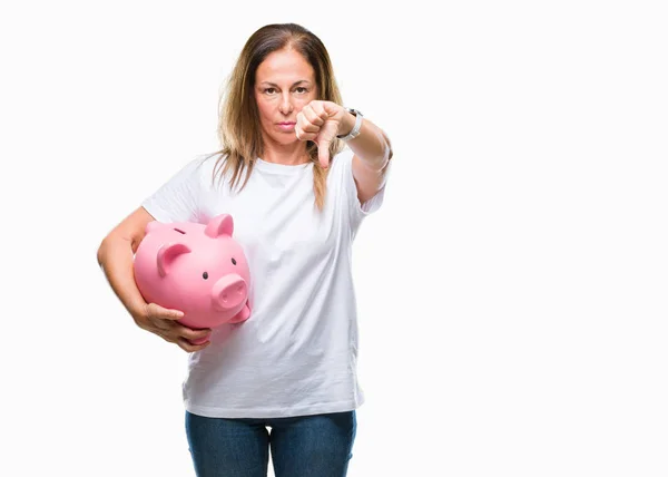 中年西班牙妇女存钱使用存钱罐在孤立的背景与愤怒的脸 显示不喜欢大拇指的负号 拒绝的概念 — 图库照片
