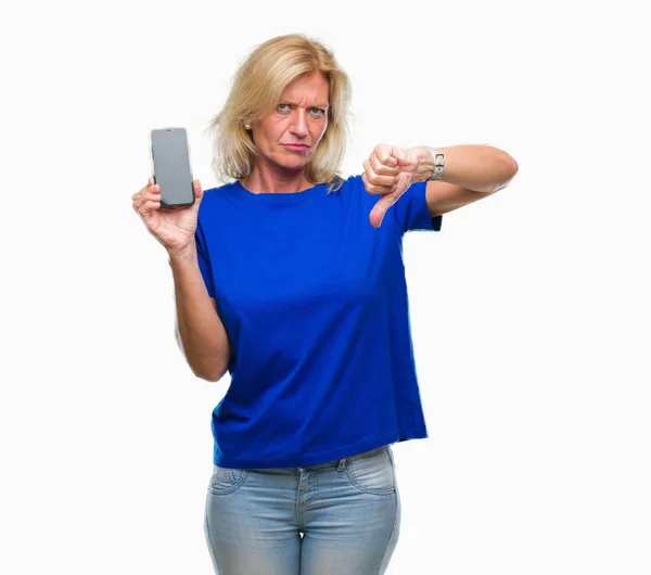 中年金髪女性は怒った顔 ダウン親指で嫌悪感を示すマイナス記号 拒絶反応の概念と分離の背景にスマート フォンの空白の画面を表示 — ストック写真