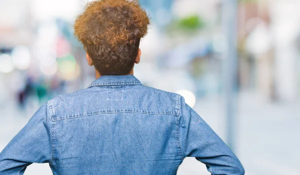 Geriye doğru uzakta silah ile vücut üzerinde seyir kot ceket ayakta giyen afro saçlı Genç yakışıklı adam