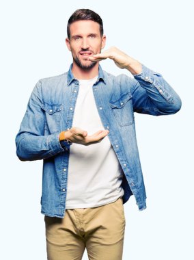 Denim ceket eller eller büyük gösterilen ve büyük boy işareti, ölçü birimi sembolü ile giyen sakal ve mavi gözlü yakışıklı adam. Kameraya bakarak gülümsüyordu. Ölçüm kavramı.