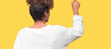 Güzel genç Afro-Amerikan kadın giyiyor kış kazak izole üzerinde arka plan geriye doğru arkasında parmak eliyle işaret Posing