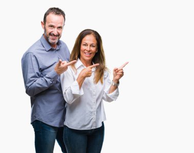 Orta yaş İspanyol iş çift gülümseyen ve iki elleri ve parmakları ile tarafına işaret kamera bakarak izole arka plan üzerinde.