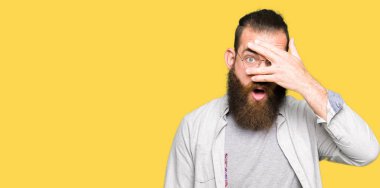 Mahcup ifadeyle parmaklarımın arasından görünen yüz ve gözler el ile kapsayan şok bakmak gözlük takan genç sarışın adam.