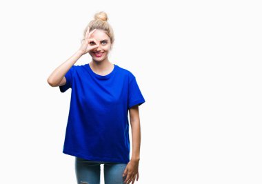 Gülümseyen, parmakları ile mutlu yüz üzerinden seyir göz el ile ok jest yapıyor izole arka plan üzerinde mavi t-shirt giyen genç güzel sarışın ve mavi gözlü kadın.