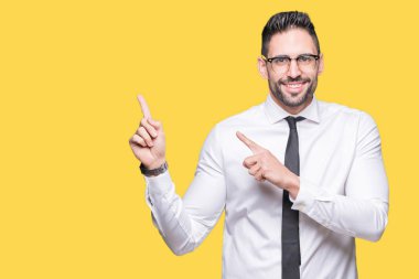 Gülümseyen ve iki elleri ve parmakları ile tarafına işaret kamera bakarak izole arka plan üzerinde gözlük takan genç yakışıklı iş adamı.