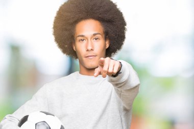 Kamera ve size parmak ile işaret futbol futbol topu tutan afro saçlı genç Afro-Amerikan adam, el işareti, pozitif ve kendinden emin bir jest ön