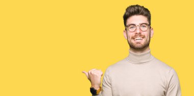 Seyir ve başparmak yanında yukarıyı mutlu yüz ile gülümseyen gözlüklü genç yakışıklı iş adamı.