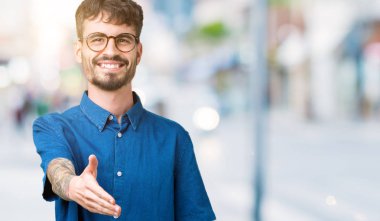 Tebrik ve davet edici dostu sunan karşılıklı gülümseyen izole arka plan üzerinde gözlük takan yakışıklı delikanlı. Başarılı iş.