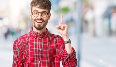 Başarılı fikirle izole arka plan işaret parmağı üzerinde gözlük takan yakışıklı delikanlı. Çıktıktan ve mutlu. Bir numara.