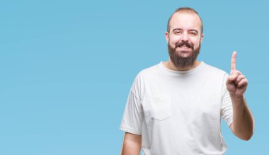 Ve parmak gülümseyen süre bir numara ile kendinden emin ve mutlu yukarıyı gösteren izole arka plan üzerinde rahat t-shirt giyen genç beyaz hipster adam.