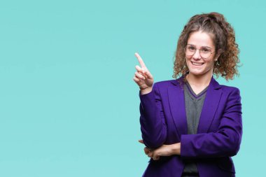 Yüzünde kocaman bir gülümseme ile izole arka plan üzerinde okul üniforması ve gözlük giyen genç esmer öğrenci kız kameraya bakarak yan el ve parmak ile işaret.