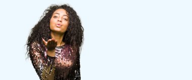 Kıvırcık saçlı bir öpücük el ile güzel ve seksi olmak hava üfleme kamera bakarak gece parti elbise genç güzel kız. Aşk ifade.