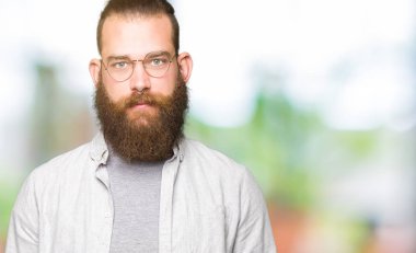 Gevşek ciddi ifade ile yüzünde gözlüklü genç sarışın adam. Basit ve doğal kameraya bakıyor.