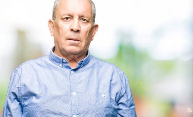 Yakışıklı üst düzey businesss adam yüzünde ciddi bir ifade ile şık gömlek giymiş. Basit ve doğal kameraya bakıyor.