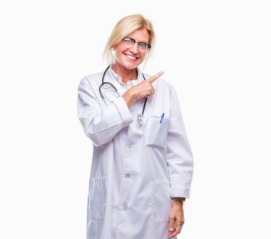 Orta yaş sarışın doktor kadın izole arka neşeli bir gülümseme ile el ve parmak kadar kameraya bakarak yüzündeki mutlu ve doğal ifade ile yan ile işaret eden yüz.