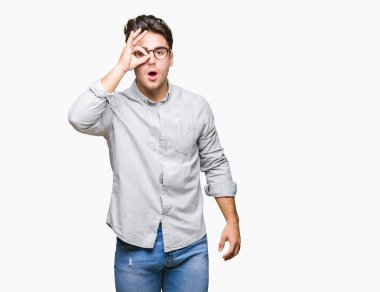 Sürpriz yüz, göz parmaklarının arasından seyir ile ok jest yapıyor izole arka plan üzerinde gözlüklü genç yakışıklı adam şok. İmansız ifade.