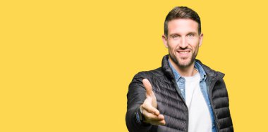 Yakışıklı adam olarak tebrik ve konuksever dost sunan karşılıklı gülümseyen kış palto giyiyor. Başarılı iş.