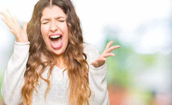 年轻的美丽的女人穿着白色毛衣庆祝疯狂和疯狂的成功与手臂抬起和闭上眼睛尖叫兴奋 优胜者概念 — 图库照片