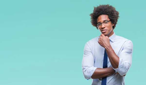 Afro american business man wearing glasses over isolated background looking confident at the camera with smile with crossed arms and hand raised on chin. Thinking positive.