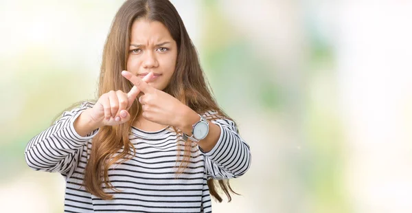 年轻美丽的黑发女人穿着条纹毛衣在孤立的背景拒绝表达交叉手指做消极的标志 — 图库照片