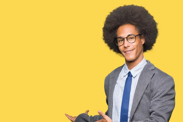 Young african american business man with afro hair wearing glasses Inviting to enter smiling natural with open hand