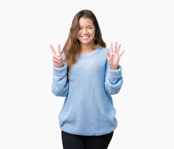 年轻美丽的黑发女人穿着蓝色的冬季毛衣在孤立的背景显示和手指指向数字 同时微笑着自信和快乐 — 图库照片