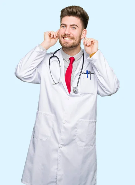 Joven Médico Guapo Con Abrigo Médico Sonriendo Tirando Las Orejas — Foto de Stock