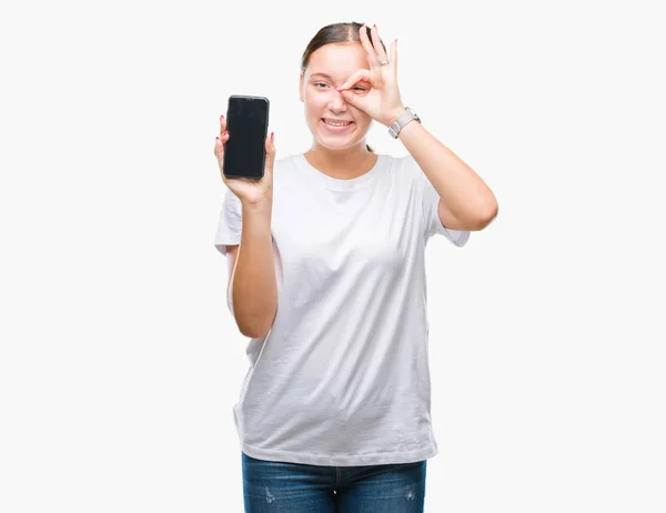 年轻美丽的高加索妇女显示智能手机屏幕在孤立的背景与快乐的脸微笑做确定的标志与眼睛看着通过手指 — 图库照片