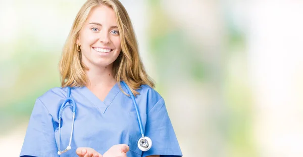 美丽的年轻医生妇女穿着医疗制服在孤立的背景微笑与手手掌一起接受或给手势 保持和保护 — 图库照片