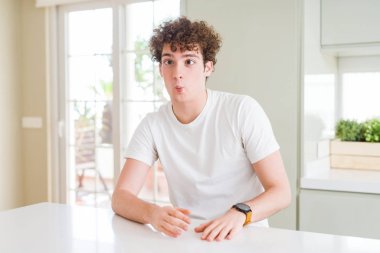 Genç yakışıklı ev yapma balık yüzüne dudaklı, çılgın ve komik bir jest giyen beyaz t-shirt adam. Komik ifade.