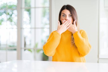 Evde kış kazak giyen genç güzel kadın kapsayan ağız elle hata için şok. Gizli kavramı.