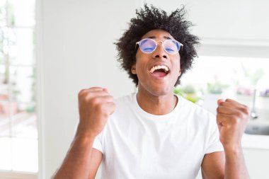 Afrika kökenli Amerikalı adam silah ile başarı için heyecanlı gözlüklü zafer kutluyor gülümseyen kaldırdı. Kazanan kavramı.