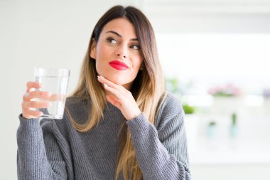 Genç güzel kadın bardak su içme çok soru hakkında ev ciddi yüz düşünme, fikir karışık