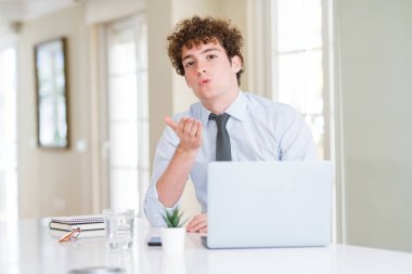 Bir öpücük el ile güzel ve seksi olmak hava üfleme kamera bakarak ofiste bilgisayar laptop ile çalışan genç iş adamı. Aşk ifade.