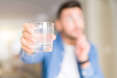 Yakışıklı delikanlı bir bardak su içme çok soru hakkında ev ciddi yüz düşünme, fikir karışık