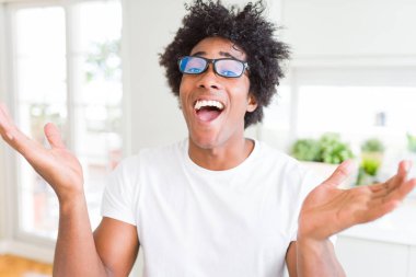 Afrikalı-Amerikalı dostum deli ve çığlık kaldırdı ve açık gözleri heyecanlı silah ile başarı için hayran kutluyor gözlük takıyorsun. Kazanan kavramı