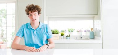 Ev seksi bir ifadeyle, neşeli ve mutlu yüzünü kameraya bakarak göz kırpıyor, genç yakışıklı adamın geniş çekim.