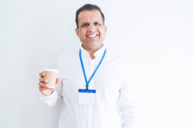 Kimlik kartı takıyor ve coffeeover beyaz arka plan ayakta ve diş gösterilen kendine güvenen bir gülümsemeyle gülümseyerek mutlu bir yüz ile içme orta yaş iş adamı