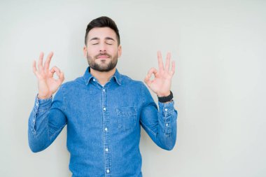 Yakışıklı delikanlı izole arka plan üzerinde dinlenmek ve gülümseyen gözlerle parmak ile meditasyon jest yapıyor kapalı. Yoga kavramı.