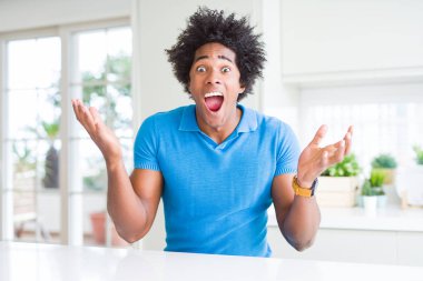 Afrika kökenli Amerikalı adam evde çılgın ve başarı için hayran kaldırdı Kollarını açarak kutluyor ve heyecanlı çığlık gözleri açık. Kazanan kavramı