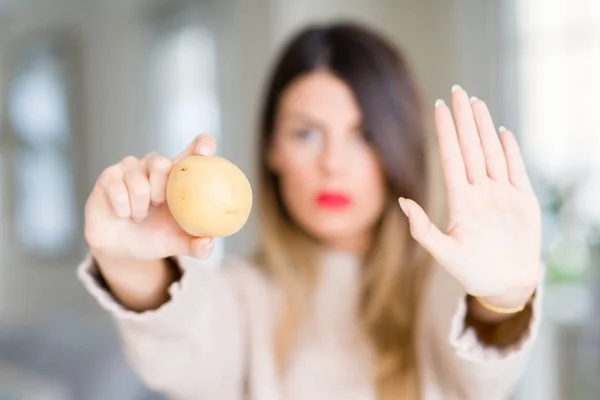 自宅で新鮮なジャガイモを保持している若い美しい女性が防衛ジェスチャー 深刻な自信を持って式に一時停止の標識をやって手を開いてください — ストック写真