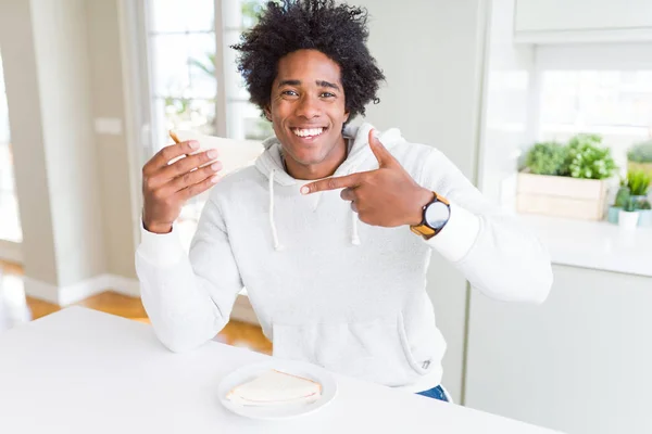 Uomo Afroamericano Mangiare Panino Fatto Mano Casa Molto Felice Indicando — Foto Stock