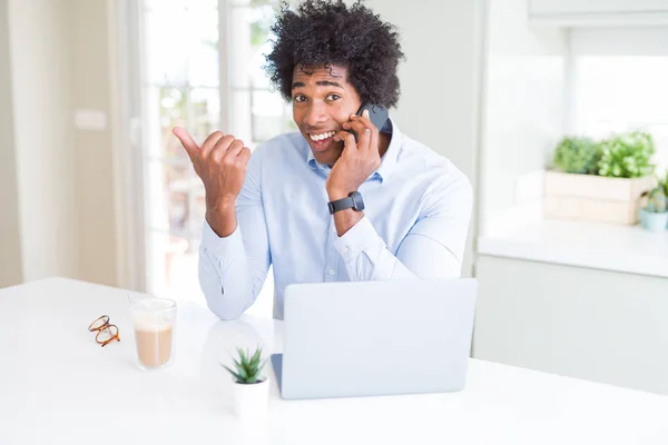 指していると幸せそうな顔を笑顔で側まで親指で示す電話で話しているアフリカ系アメリカ人のビジネスマン — ストック写真