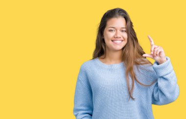 İzole arka plan gülümseyen ve süre seyir ve kamera boyutu işaret parmaklarıyla yapıyor el ile kendinden emin eller üzerinde mavi kış kazak giyen genç güzel esmer kadın. Ölçü kavramı.