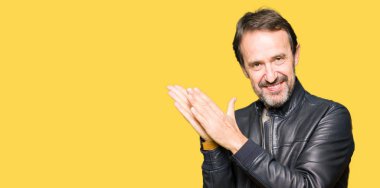 Siyah deri giyen orta yaş yakışıklı adam ceket Clapping ve mutlu ve neşeli, gururlu gülümseyen birlikte eller alkış