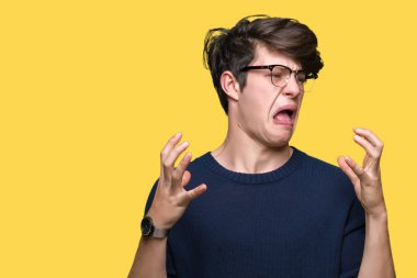 Üzerinde gözlük takan genç yakışıklı adam arka plan deli izole ve deli bağırarak ve agresif ifade ve silah kaldırdı bağırıyor. Hayal kırıklığı kavramı.