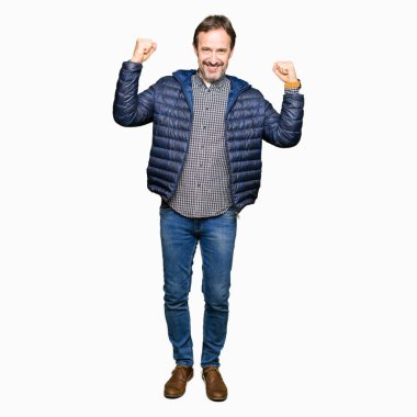 Orta yaş yakışıklı adam kol kasları gururlu gülümseyen gösterilen kış palto giyiyor. Fitness kavramı.