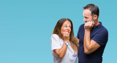 Orta yaş İspanyol rahat çift stresli ve gergin ile izole arka plan üzerinde tırnak ısırma dudaklarından eller. Anksiyete sorunu.